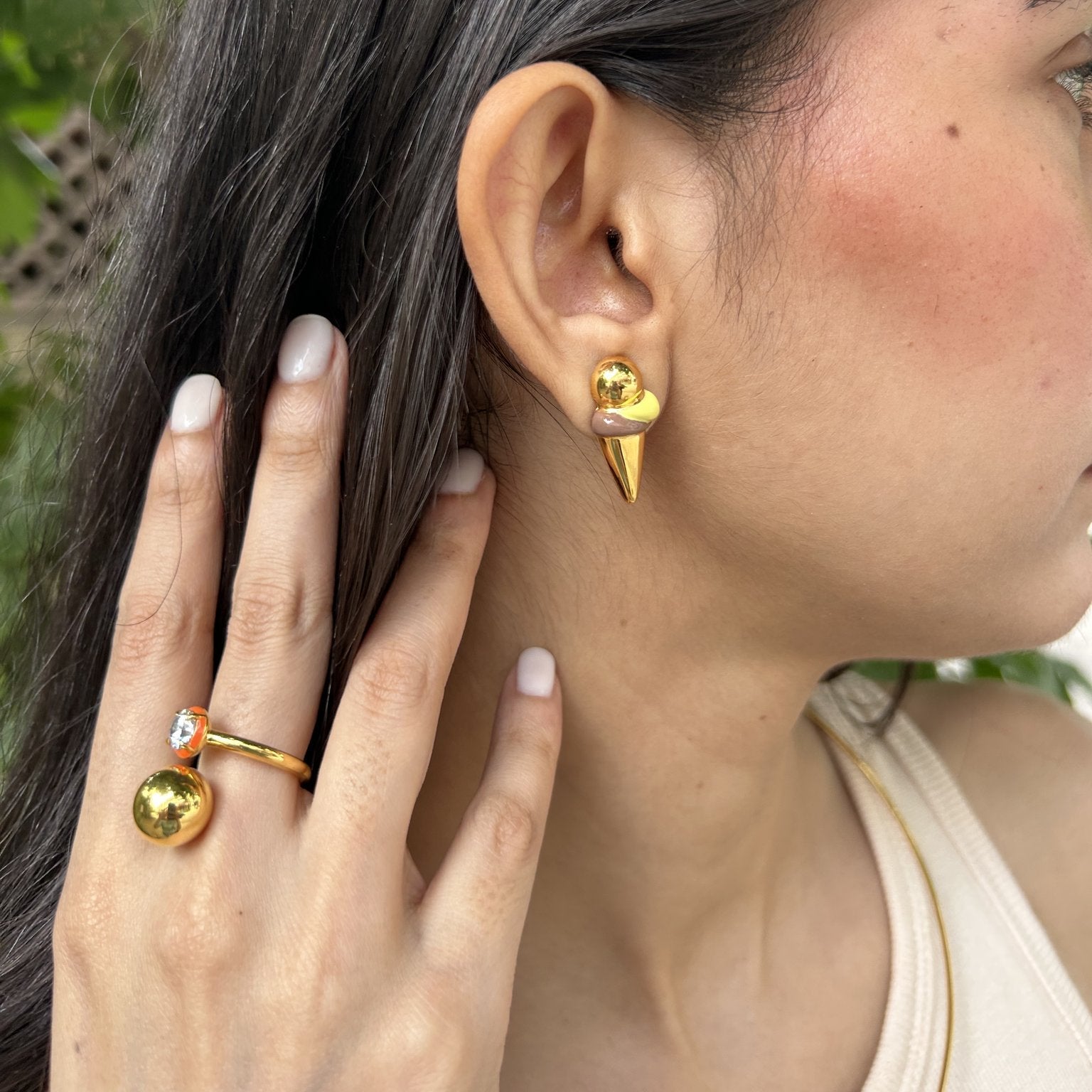 Woman wearing gold earrings and ring with a natural background